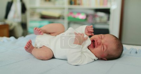 Photo for Cute newborn baby yawning laid in bed - Royalty Free Image