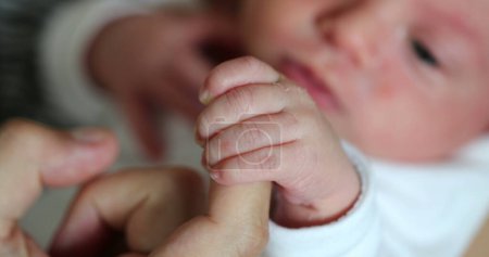 Téléchargez les photos : Cute newborn baby hand holding to father finger. Dad supporting infant newborn - en image libre de droit