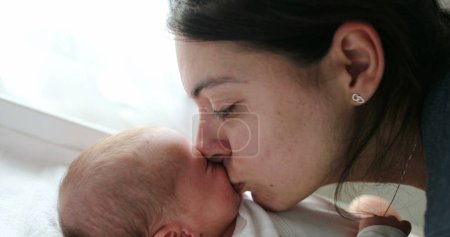 Téléchargez les photos : Mom kissing newborn baby son in the cheek - en image libre de droit