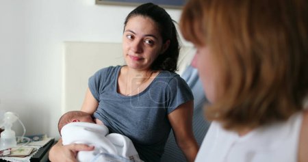 Photo for Friends in conversation about maternity parent holding newborn baby speaking to female friend - Royalty Free Image