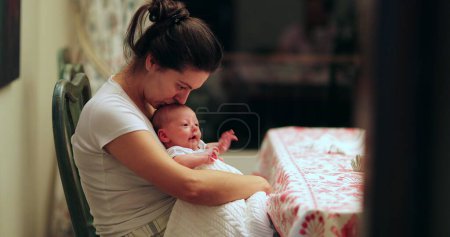 Photo for Candid mother kissing month old baby newborn infant at home casual - Royalty Free Image
