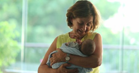 Téléchargez les photos : Happy Grand-mother calming and holding newborn baby in arms - en image libre de droit