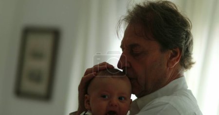 Foto de Authentic grandfather holding baby infant toddler at home - Imagen libre de derechos