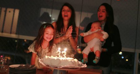 Photo for Authentic birthday celebration family members singing happy birthday and blowing candles on cake - Royalty Free Image