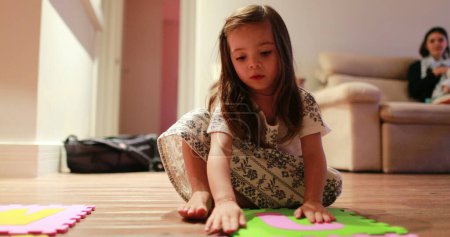 Téléchargez les photos : Petite fille enfant jouer avec des morceaux de puzzles à la maison - en image libre de droit
