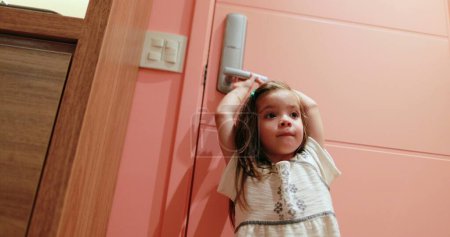 Téléchargez les photos : Petite fille enfant tenant bouton de porte voulant sortir - en image libre de droit