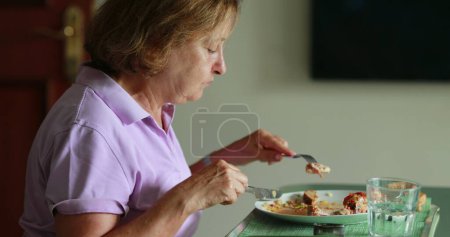Foto de Older woman eating lunch candid authentic - Imagen libre de derechos