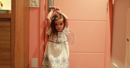 Téléchargez les photos : Petite fille tenant le bouton de porte attendant que le parent arrive à la maison - en image libre de droit