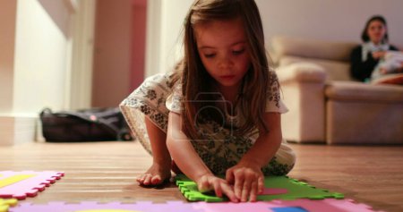 Téléchargez les photos : Petite fille enfant jouer avec des morceaux de puzzles à la maison - en image libre de droit