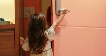 Foto de Niña niña abriendo puerta principal dando la bienvenida a miembro de la familia - Imagen libre de derechos