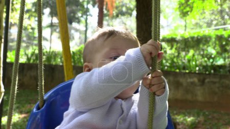 Téléchargez les photos : Bébé garçon au parc de jeux swing bébé au parc à l'extérieur - en image libre de droit