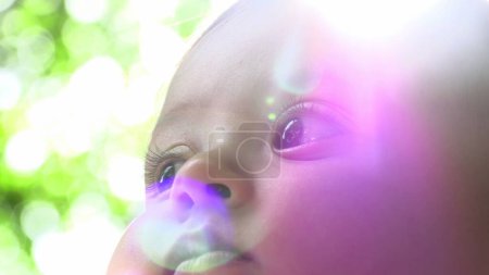 Téléchargez les photos : Beau portrait de visage de bébé à l'extérieur avec sunflare bébé observant - en image libre de droit