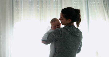 Photo for Revealing Candid mother holding and consoling crying baby good for transition - Royalty Free Image