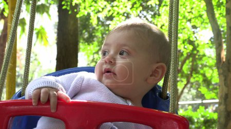 Téléchargez les photos : Bébé garçon bébé au parc swing à l'extérieur - en image libre de droit