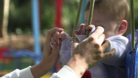 Téléchargez les photos : Bébé garçon à l'activité swing aire de jeux - en image libre de droit