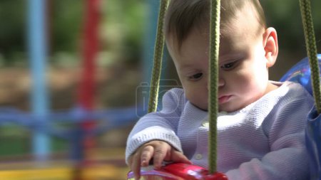 Téléchargez les photos : Bébé garçon à aire de jeux swing parc s'amuser - en image libre de droit