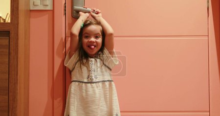 Foto de Small girl child holding door knob opening front door waiting for parent to arrive - Imagen libre de derechos