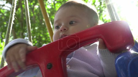 Téléchargez les photos : Adorable bébé garçon à l'oscillation de l'aire de jeux - en image libre de droit