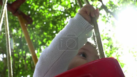 Téléchargez les photos : Bébé garçon au parc oscillant de l'aire de jeux avec lentille-fusée artistique - en image libre de droit