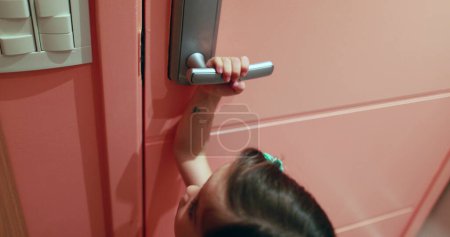 Photo for Small girl child opening front door hand holding door knob peeking out door entrance - Royalty Free Image