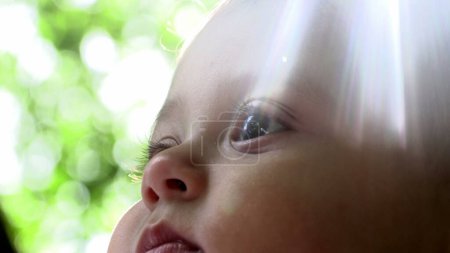 Téléchargez les photos : Belle prise de vue artistique du visage de bébé avec un soleil éclat de lentille - en image libre de droit