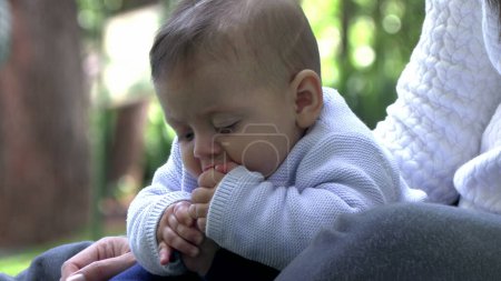 Niedliches Baby, das Fuß in den Mund setzt und Zehen erforscht, entzückendes Säugling im Freien
