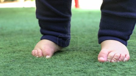 Téléchargez les photos : Gros plan de bébé pieds de bébé à l'extérieur debout en essayant d'être équilibre - en image libre de droit