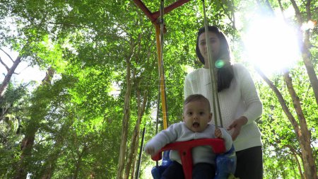 Téléchargez les photos : Bébé bébé heureux à swing aire de jeux - en image libre de droit