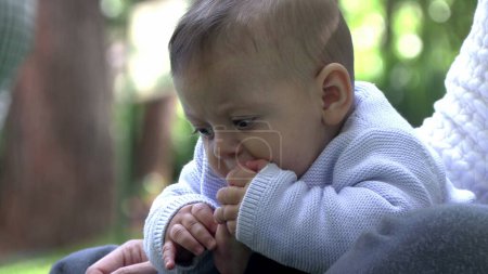 Niedliches Baby, das Fuß in den Mund setzt und Zehen erforscht, entzückendes Säugling im Freien
