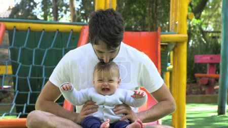 Foto de Papá sosteniendo llorando molesto bebé hijo fuera en el parque - Imagen libre de derechos