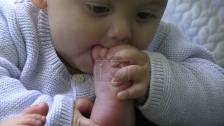 Foto de Bebé poniendo un pie en la boca y regurgitando vómitos con leche - Imagen libre de derechos