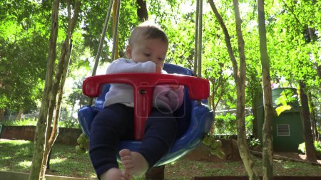 Téléchargez les photos : Bébé garçon au parc de swing aire de jeux - en image libre de droit