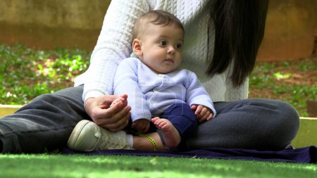 Téléchargez les photos : Mère décontractée et bébé ensemble assis au parc - en image libre de droit