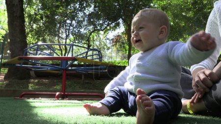 Foto de Molesto bebé infante insatisfecho sentado en el parque - Imagen libre de derechos