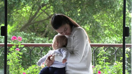 Téléchargez les photos : Maman et bébé ensemble à la fenêtre du balcon - en image libre de droit