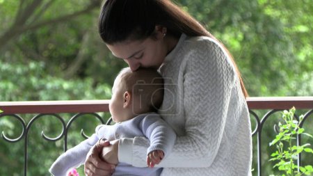 Foto de Mamá besando bebé al lado de la ventana con vistas - Imagen libre de derechos