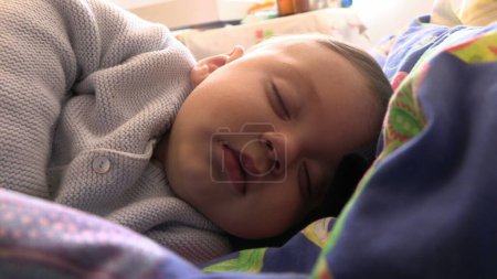 Photo for Peaceful baby toddler asleep in bed taking a nap - Royalty Free Image