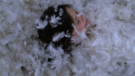 Little Girl Playing in Feather Bed, Joyful and Relaxed. Child in a Plumage Filled Bed, Peaceful and Happy