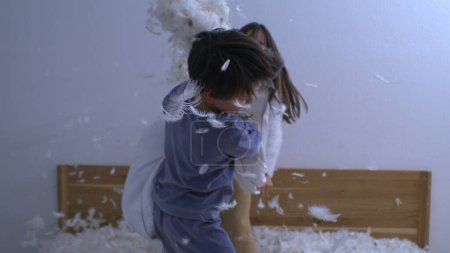 Photo for Fun children having a pillow fight with feathers flying everywhere in the air, carefree play of children captured with a high speed slow motion camera - Royalty Free Image