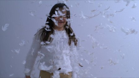 Photo for Childhood Bliss - Young Girl Covered in feathers falling from above, Tossing Feathers. - Royalty Free Image