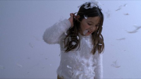 Photo for Childhood Bliss - Young Girl Covered in feathers falling from above, Tossing Feathers. - Royalty Free Image