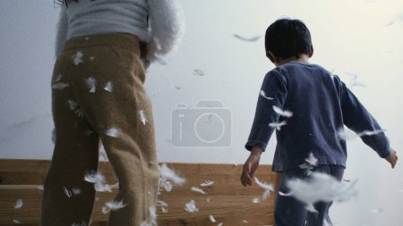 Photo for Feathers falling down from air while children in the background bounce in bed - Royalty Free Image