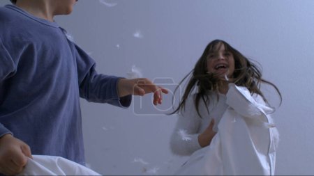 Foto de Explosión de plumas en cámara lenta: primer plano de la lucha de almohadas para niños a 1000 FPS. Hermano y hermana se dedican a divertirse en medio de plumas - Imagen libre de derechos