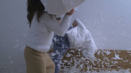 Photo for Fun playful activity of children engaged in pillow fight with feathers flying everywhere in the air captured with a high speed camera in super slow motion - Royalty Free Image