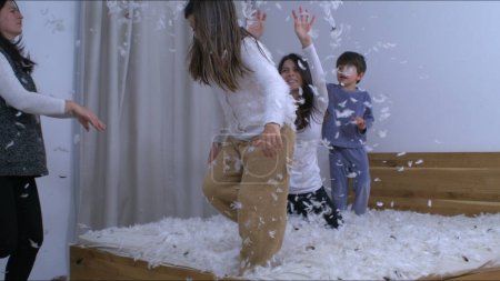 Photo for Family throwing feathers into the air in super slow motion captured in 1000 fps. People covered in plumage in carefree happy authentic moment - Royalty Free Image