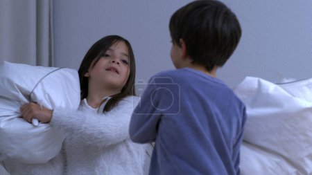 Children having fun amidst pillow fight, little brother covered in feathers during play