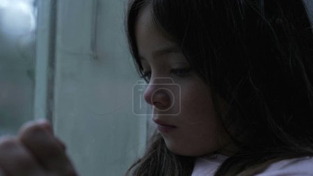 Téléchargez les photos : Triste enfant penché sur le verre dans la solitude, femme déprimée réfléchie enfant de 8 ans à la maison aux prises avec la solitude - en image libre de droit
