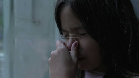 Foto de Una niña arañando la nariz debido a alergias. Primer plano de la cara del niño tocando la cara expresando reacción de malestar alérgico - Imagen libre de derechos