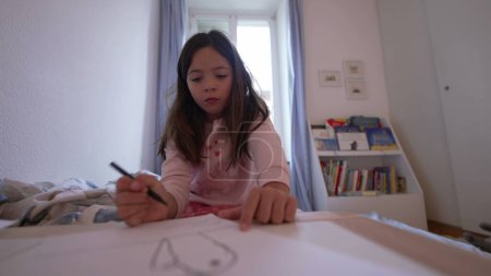 Foto de Niño enfocado que participa en actividades de dibujo en el hogar, la pluma y la artesanía de papel en el dormitorio - Imagen libre de derechos