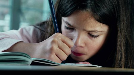 Photo for Intensely Focused Little Girl Drawing on Paper. A small girl deeply engaged in art, using a coloring pen for her creative expression, with a close-up on her face showing her artistic concentration - Royalty Free Image